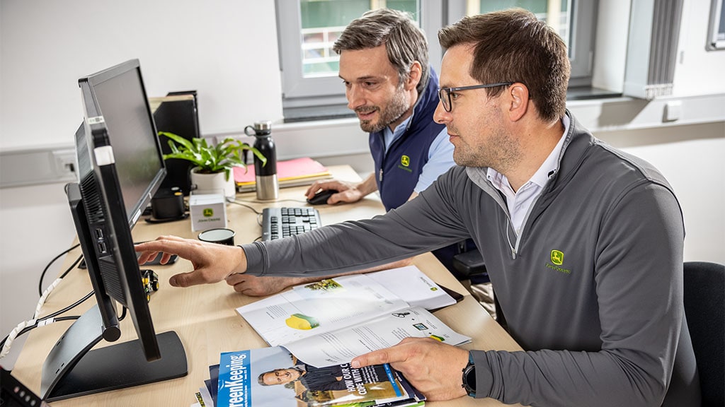 Deux personnes dans un bureau pointant vers un affichage de moniteur.