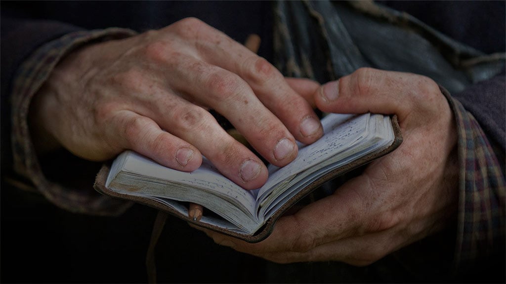 Photo de mains tenant un petit carnet ouvert