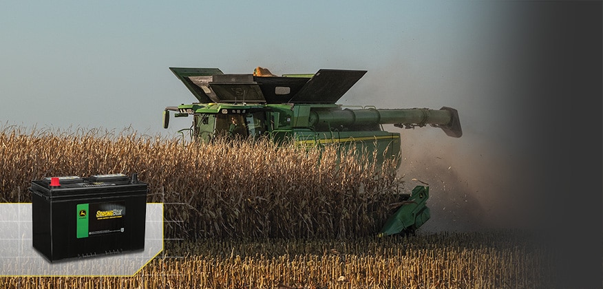 Combine harvesting corn with a John Deere StrongBox battery shown in the lower left.