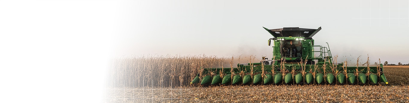 Une moissonneuse-batteuse récoltant du maïs avec un large cueilleur à maïs vert se déplaçant dans un champ.