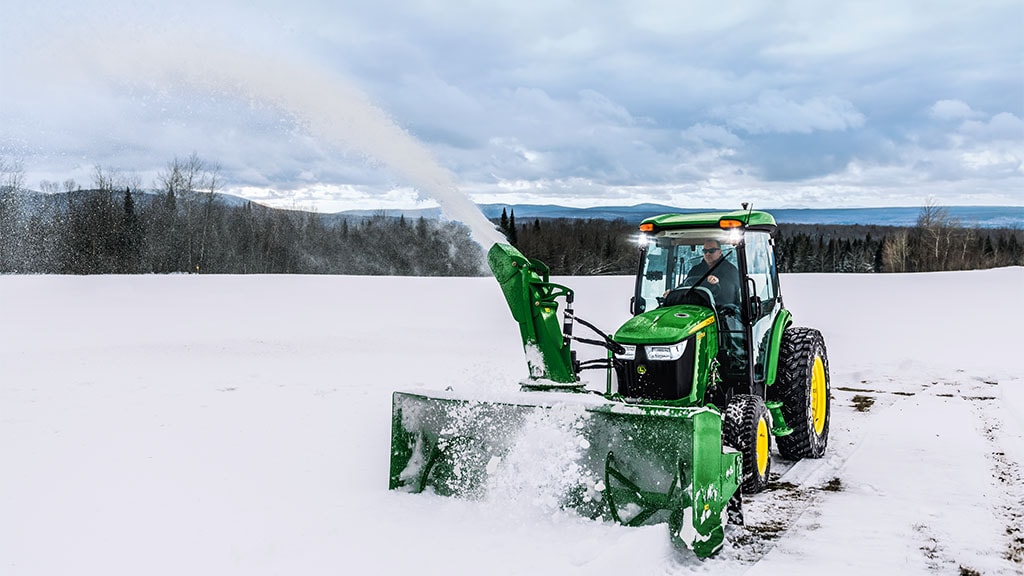 Une personne utilisant un tracteur compact 4075R équipé d’une souffleuse à neige pour déneiger.