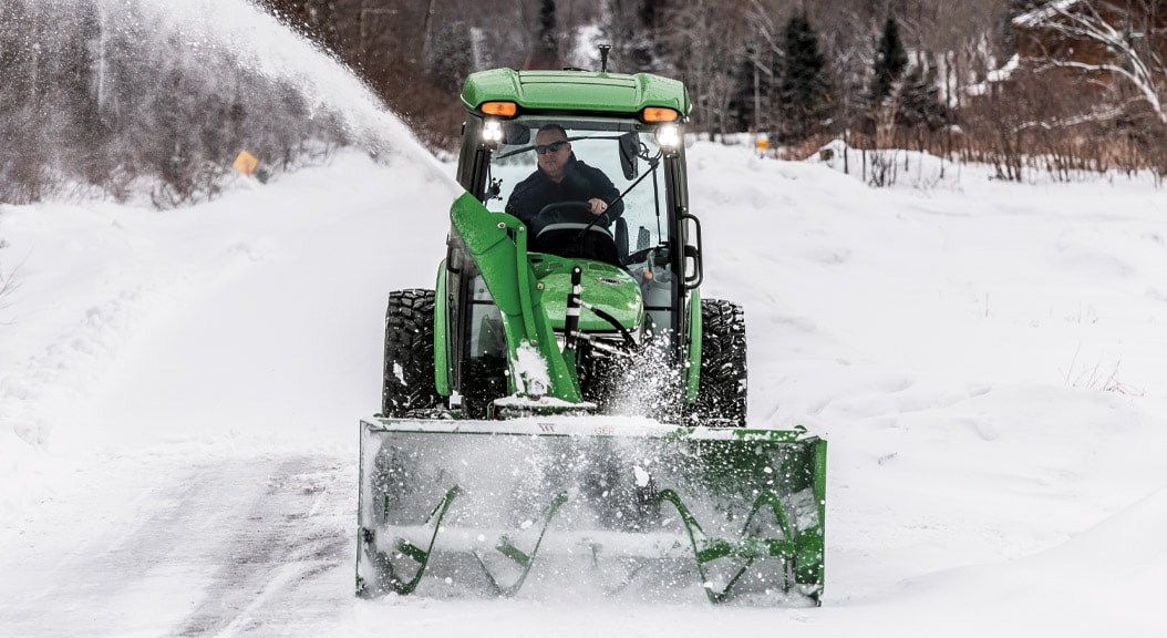 Personne soufflant de la neige avec un tracteur compact 4075R équipé d'une fraise à neige