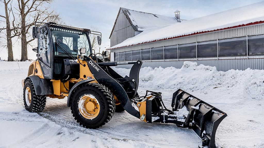 Une personne nettoyant la neige du parc de stationnement à l’aide d’une chargeuse compacte à roues