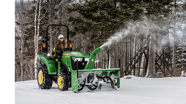 Personne déblayant la neige avec un tracteur utilitaire compact équipé d’une souffleuse à neige.
