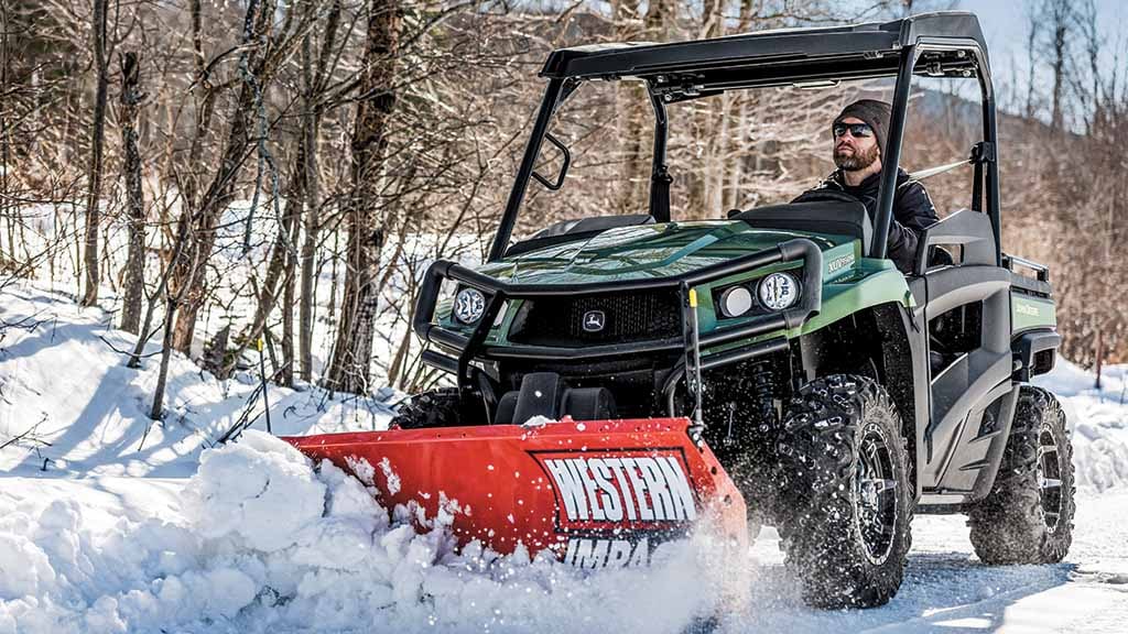 Personne déneigeant avec un véhicule utilitaire Gator™ équipé d’une lame