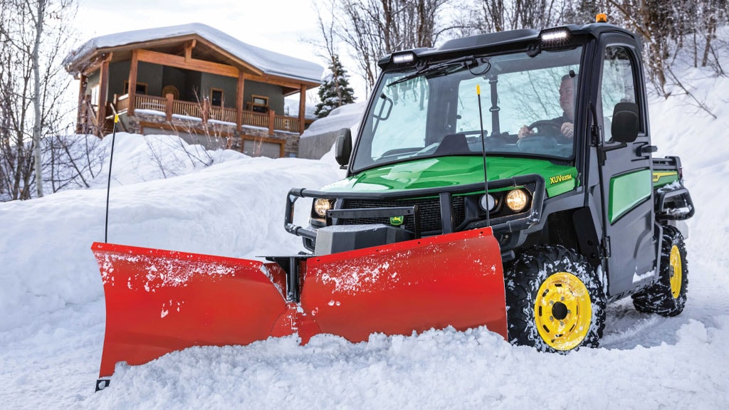 Person clearing snow with Gator XUV equipped with a blade.