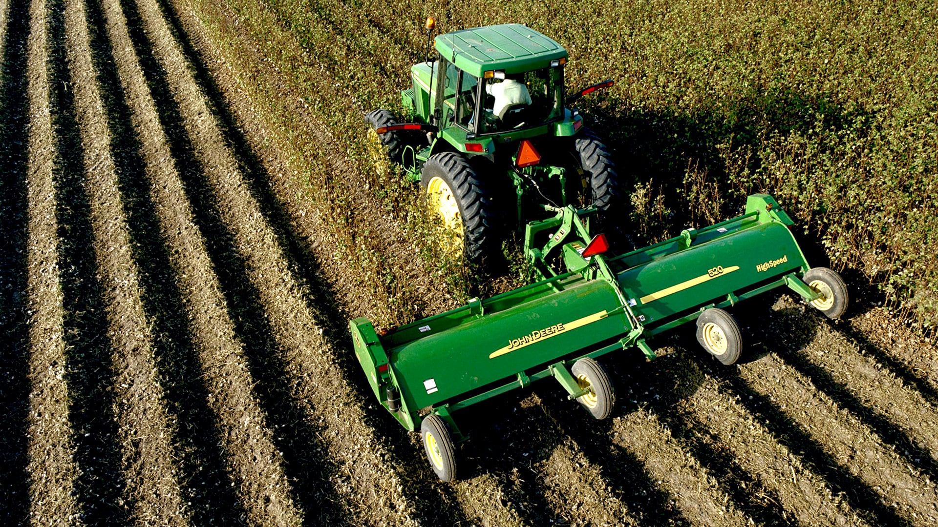 vue aérienne d’une faucheuse à fléaux fixée à un tracteur dans un champ