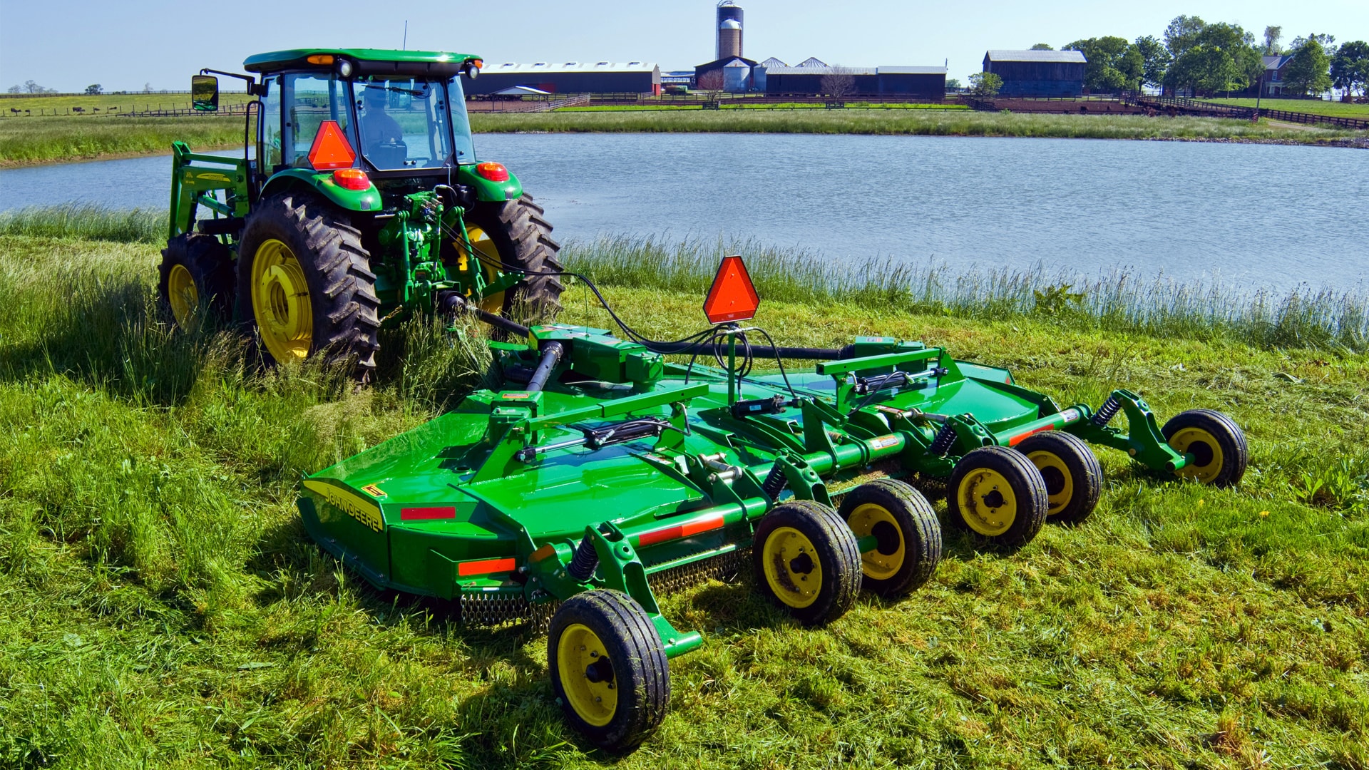 JD rotary cutter attached to tractor in field