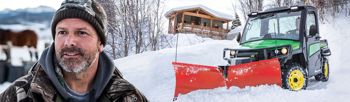 Person in snow standing in front of Gator XUV835R with V Blade
