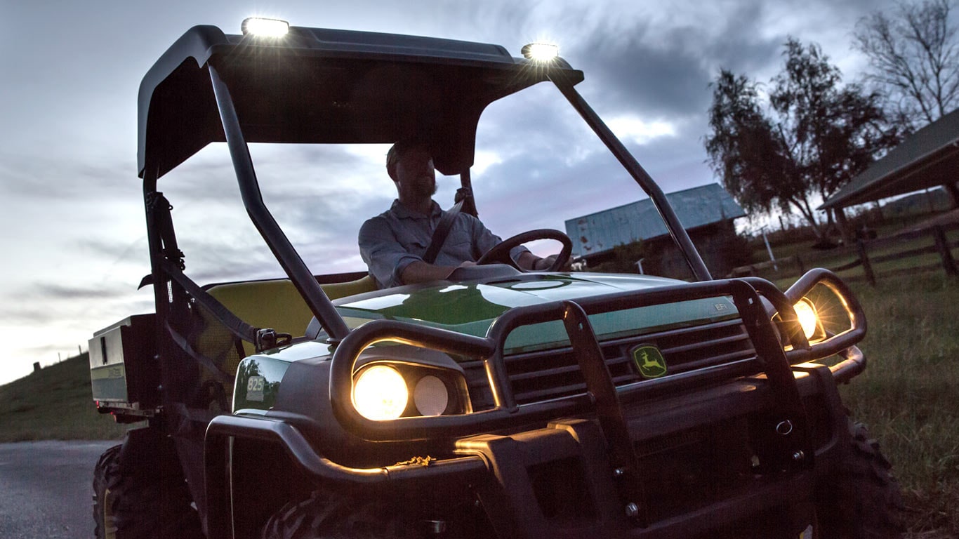 image d’un véhicule utilitaire Gator™ avec les phares allumées au crépuscule