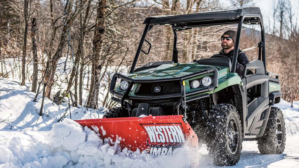 Person driving Gator moving snow with Western blade