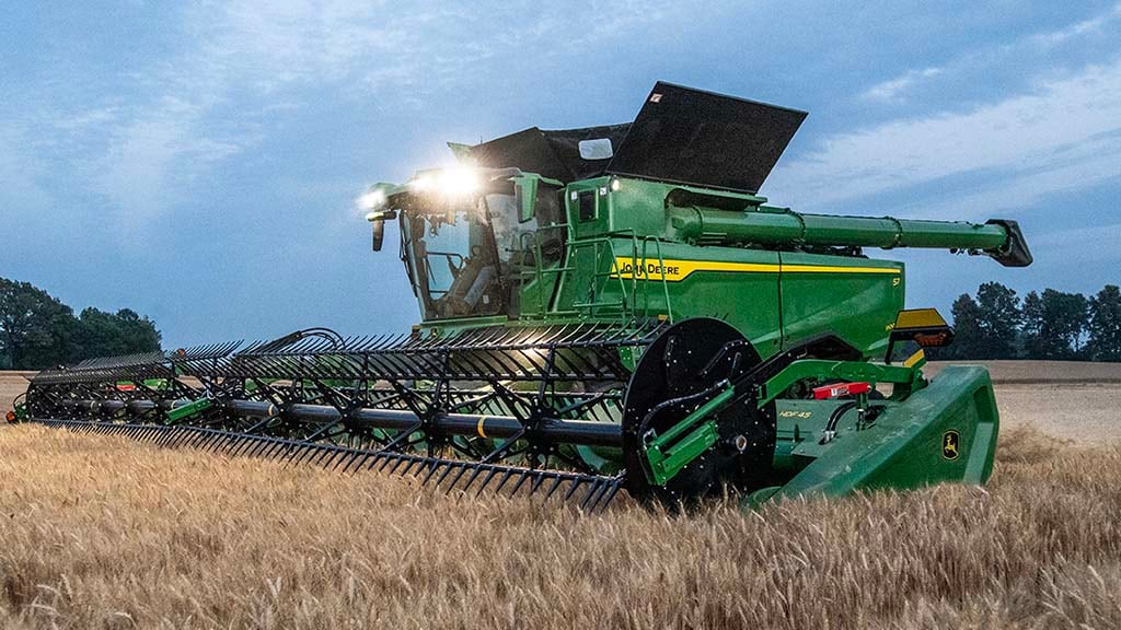 Photo d’une moissonneuse-batteuse John Deere récoltant de petits grains avec une tête de draper.