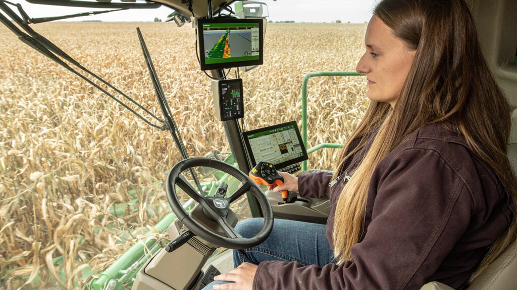 Photo d’un agriculteur dans la cabine d’une moissonneuse-batteuse S7 regardant dehors pendant qu’il récolte du maïs.