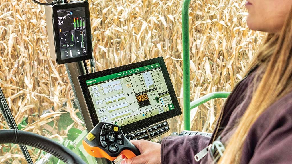 Photo à l’intérieur de la cabine d’une moissonneuse-batteuse S7 John Deere de la vue de l’agricultrice sur l’afficheur CommandCenter G5Plus pendant qu’elle récolte du maïs.