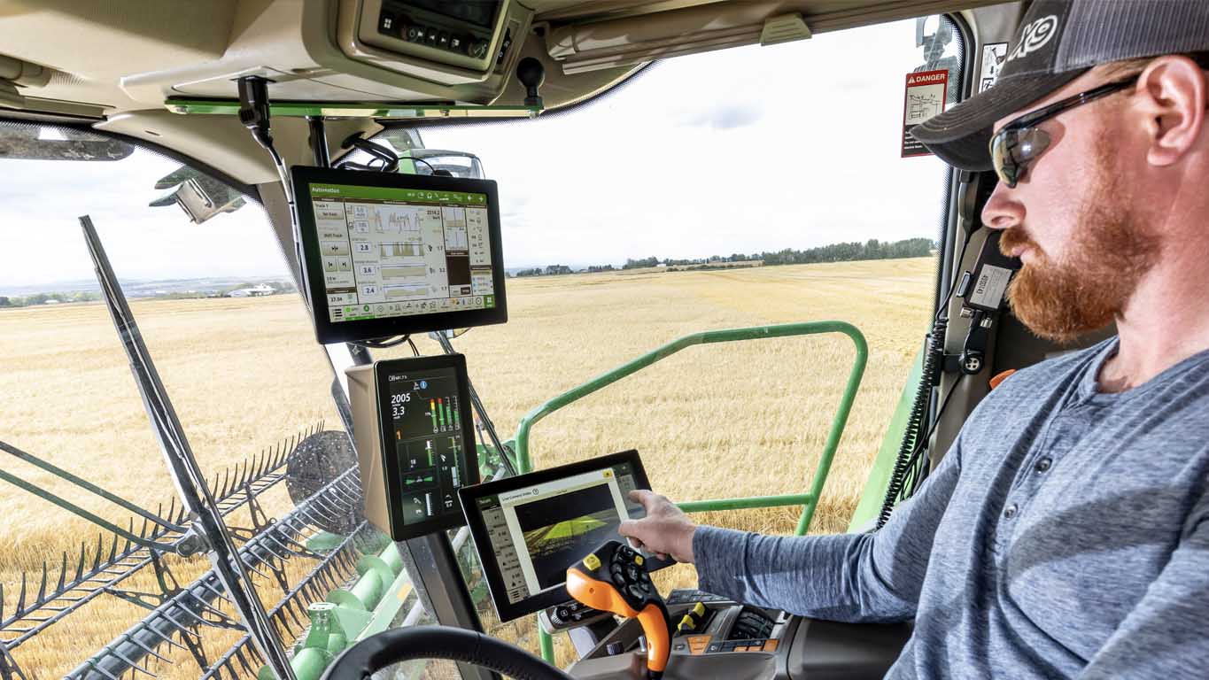 Photo dans la cabine d’un agriculteur, ajustant sa page d’exécution de l’automatisation des paramètres de récolte sur un écran G5Plus CommandCenter™