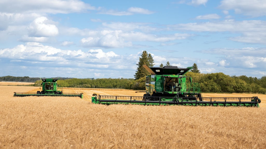 Photo de deux moissonneuses-batteuses John Deere récoltant du blé.