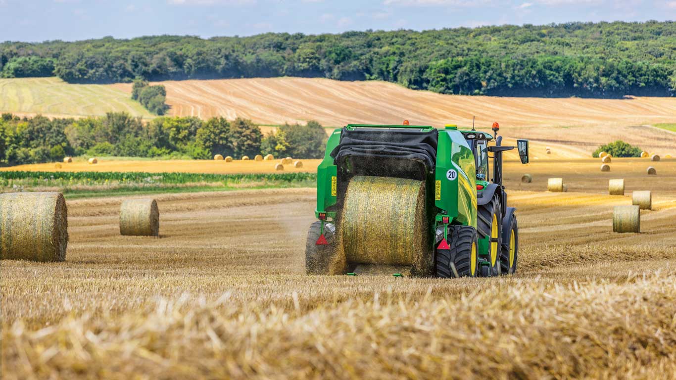 A baler ejecting a hay bale, surrounded by other hay bales