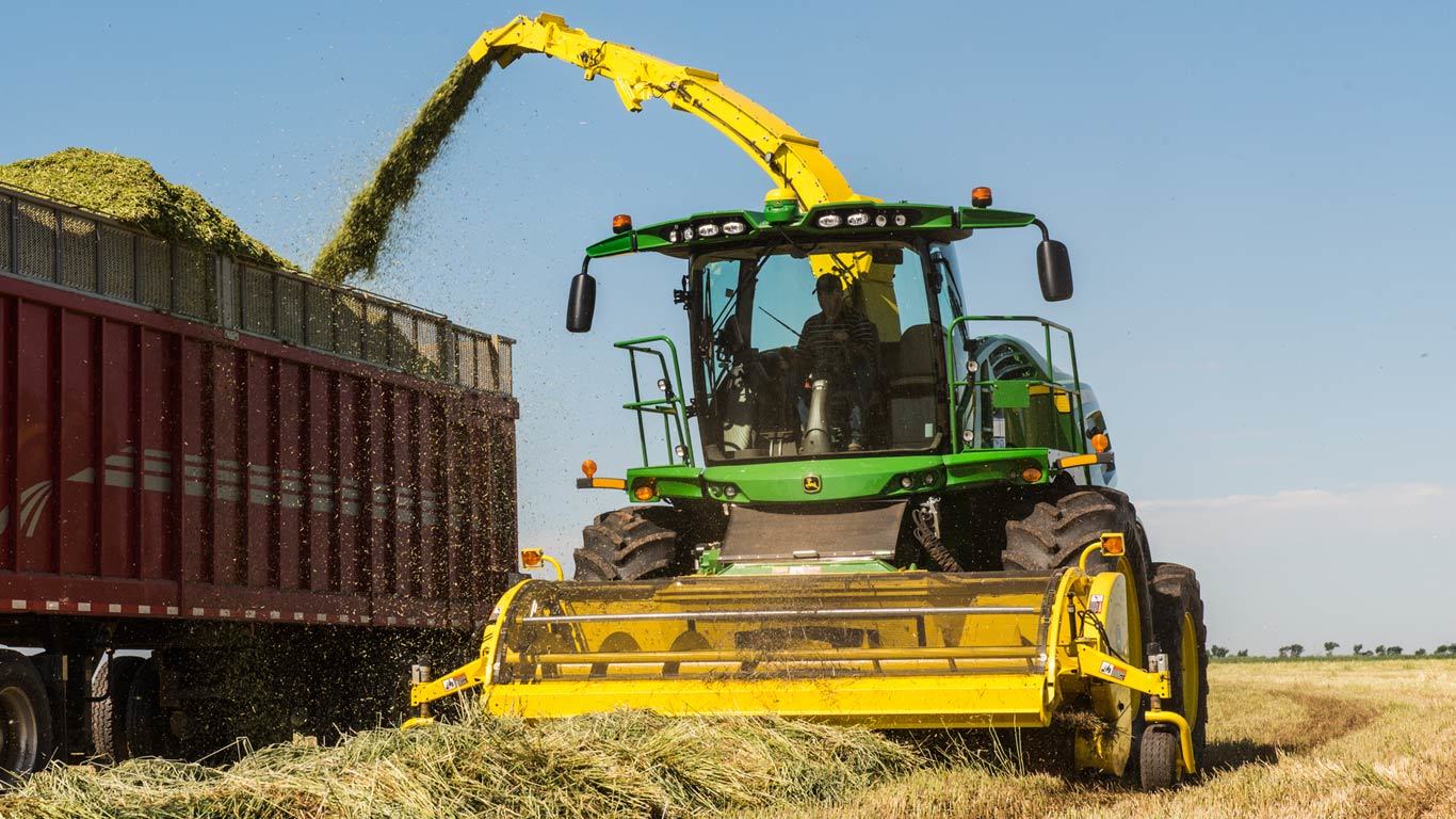 659 picking up hay in a field and dumping it into a bin