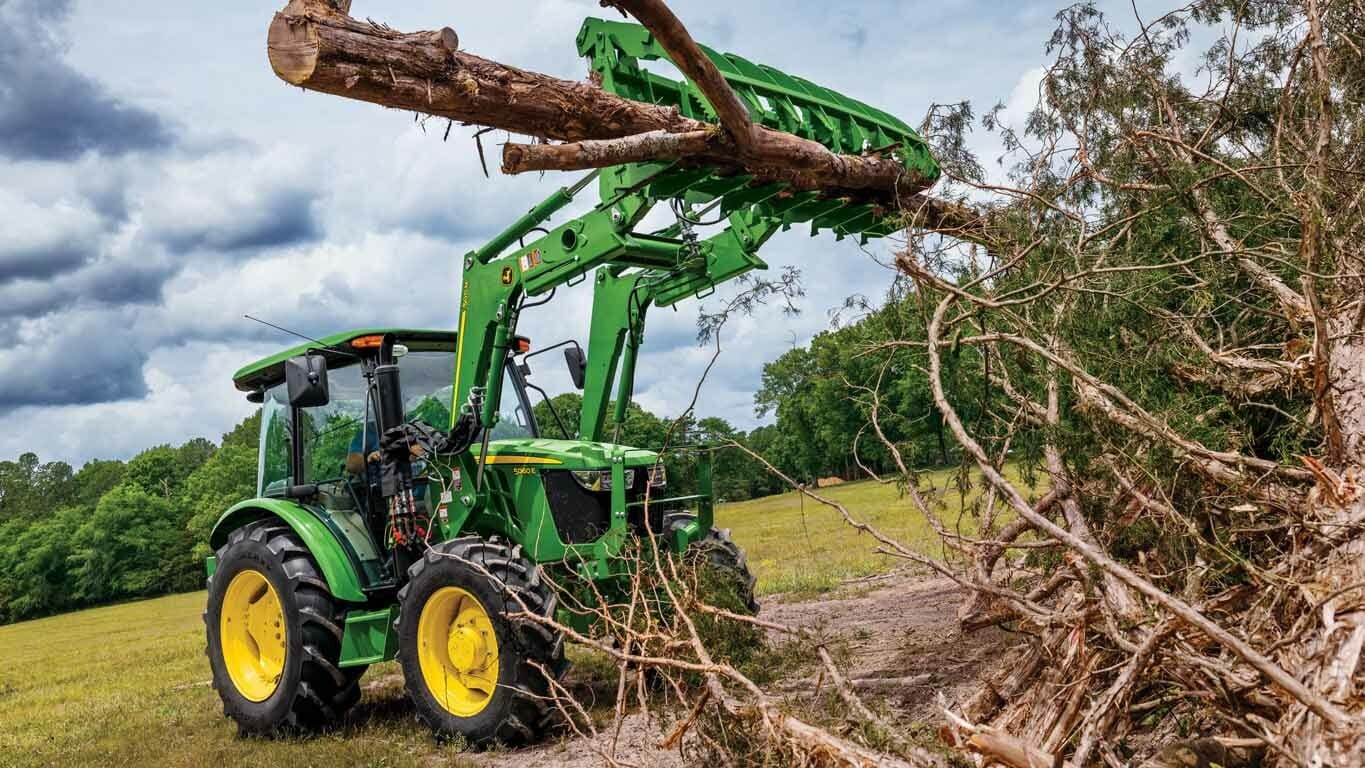 Un chargeur 500M soulevant une branche d’arbre lourde d’un grand tas de branches