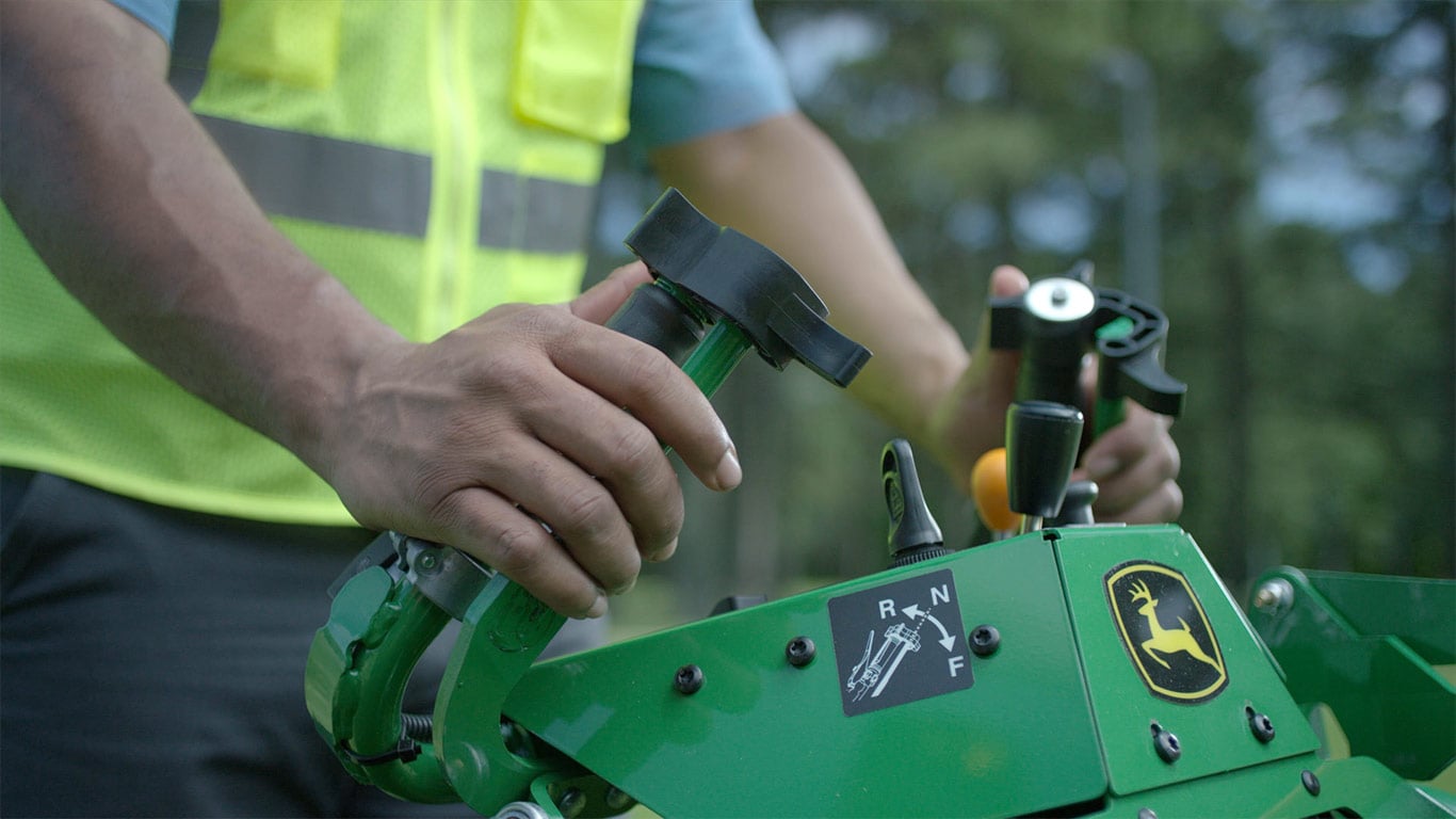 Close-up of a man's hands on the handles of a walk-behind mower