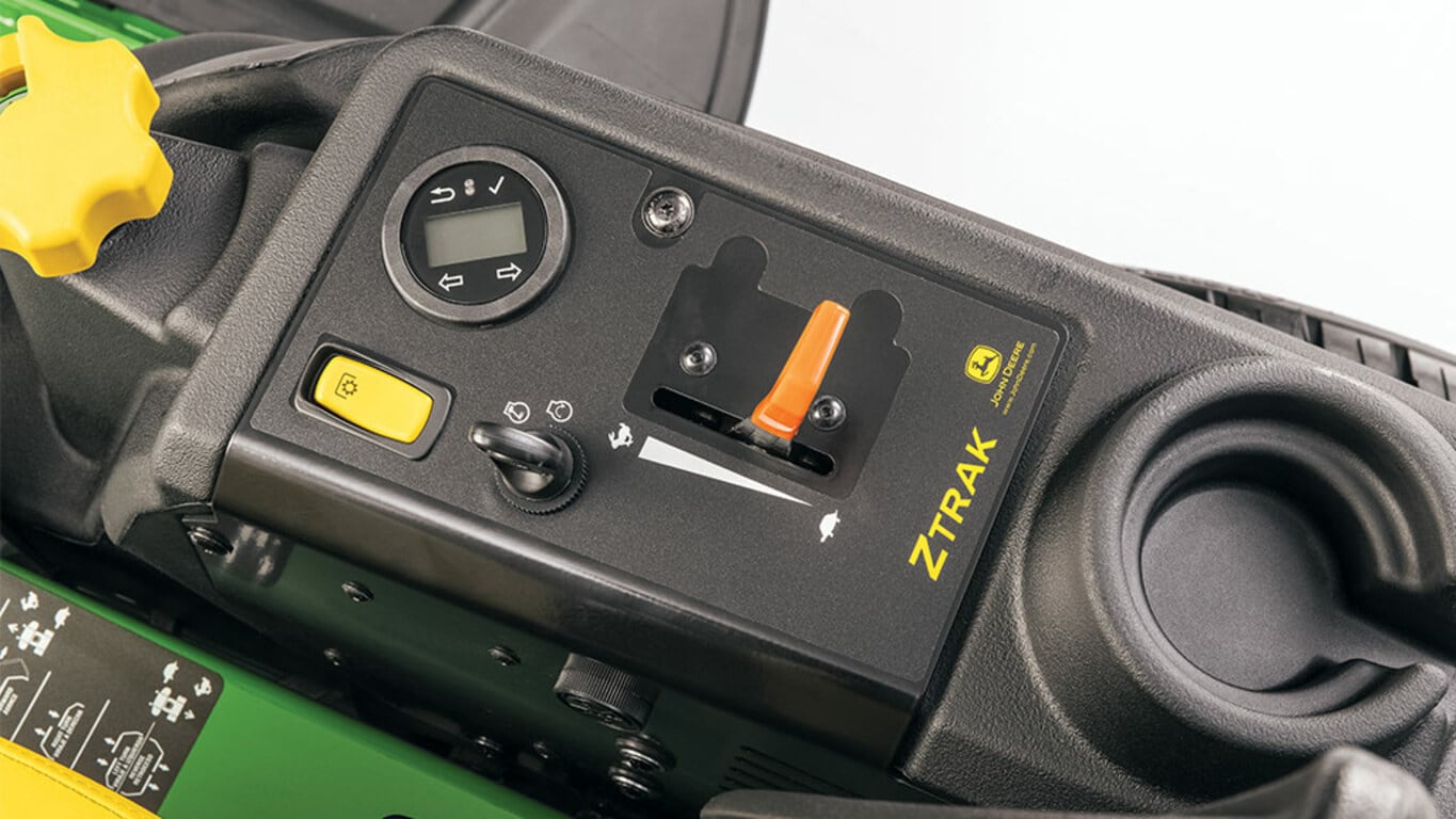 Close-up of the control console on a zero-turn mower showing the throttle, headlights switch, key ignition, and more.