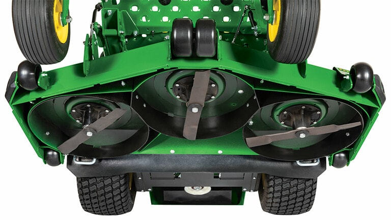 Close-up of the underside of a large green mower deck with three blades.