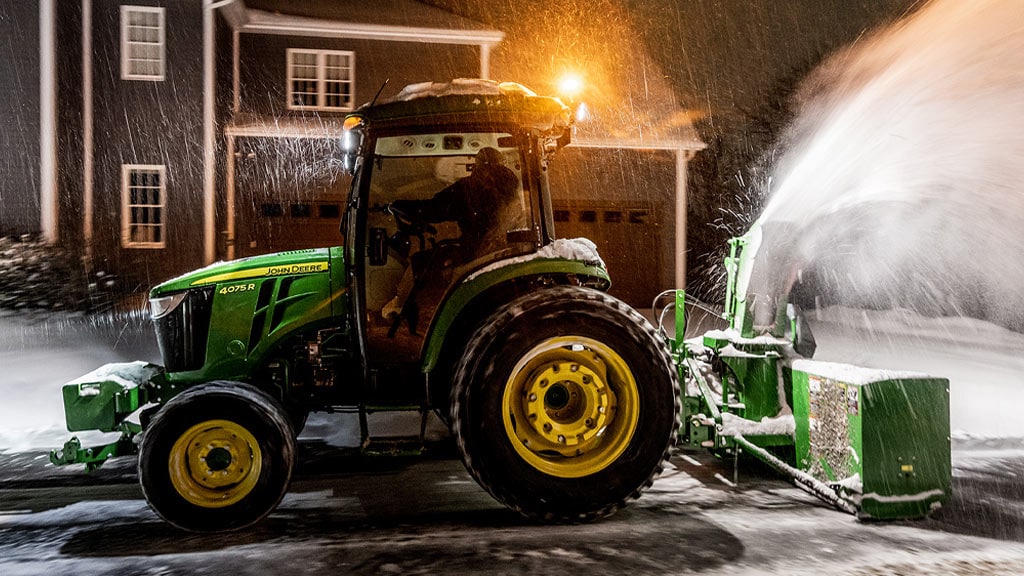 Tracteur utilitaire compact 4075R en train de déneiger près d'une maison