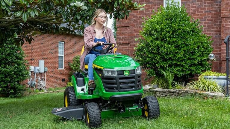 Personne au volant d’un tracteur de pelouse S110 devant une maison