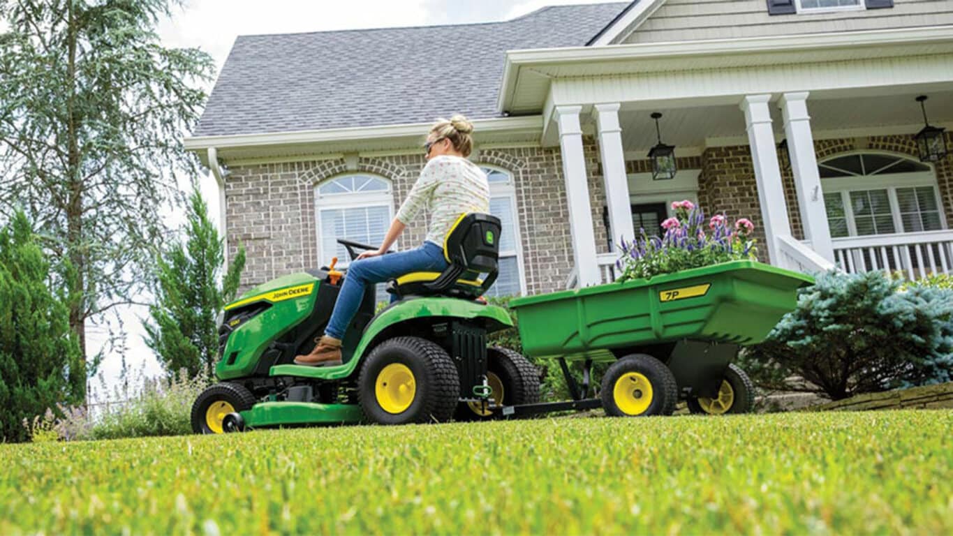Person riding a S120 mower with an attached tow cart