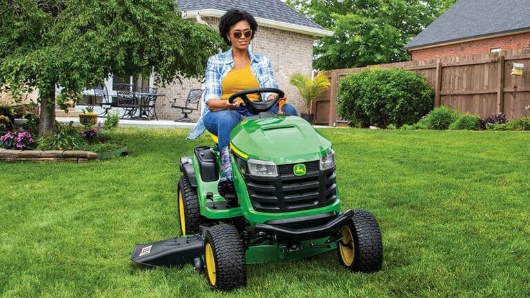 Person riding on a S170 mower near a home