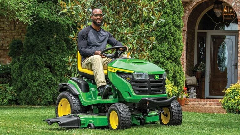 Person riding on a S180 mower near a home