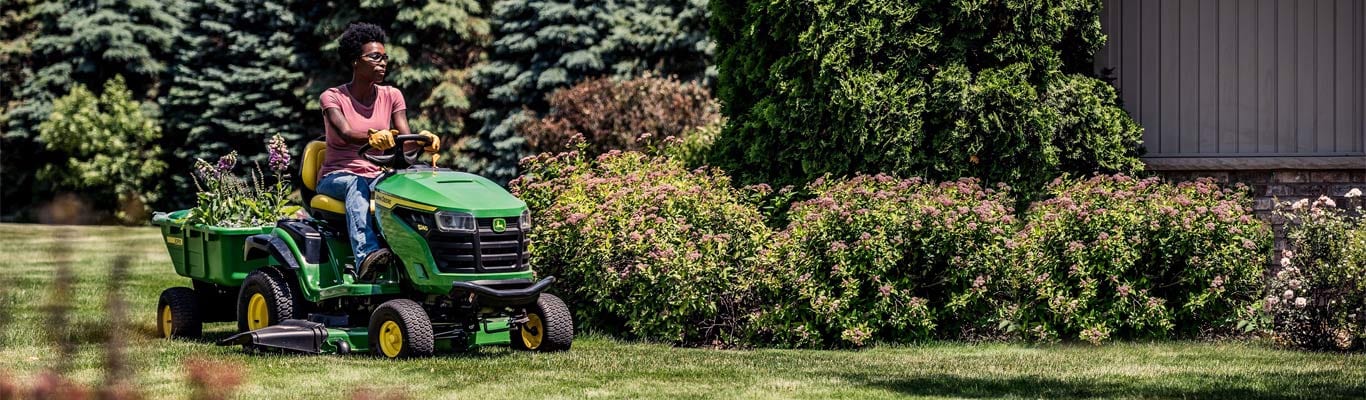 woman driving 200 series lawn tractor in yard