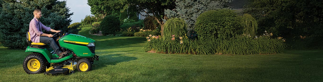 Un homme tondant sa pelouse avec un tracteur de pelouse John Deere X580 Select Series.
