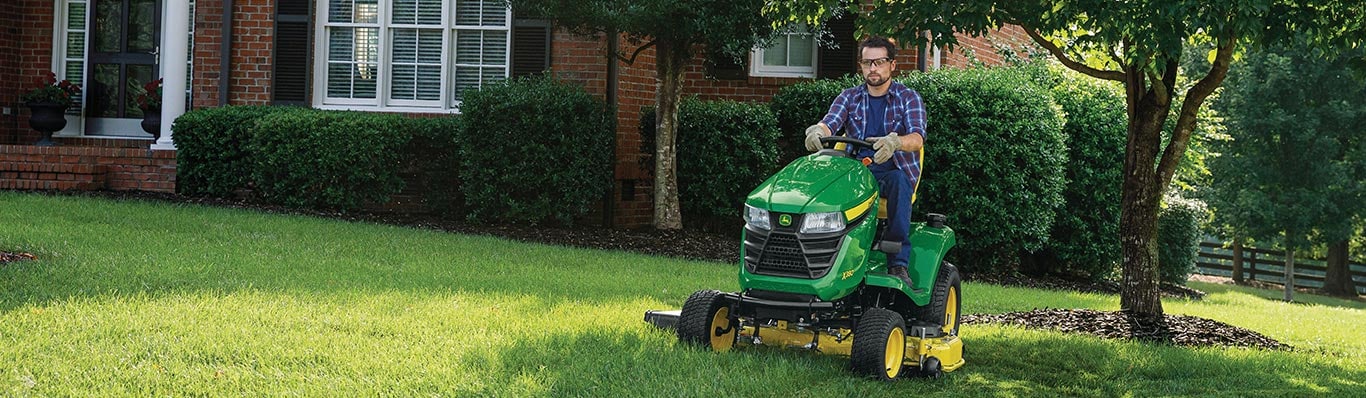man driving x300 series lawn tractor in yard