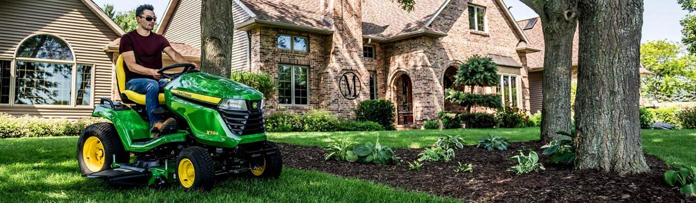 Man in maroon shirt driving a x500 lawn mower