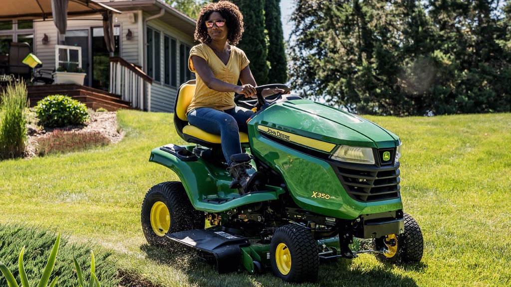 person on a lawn mower mowing grass in a field