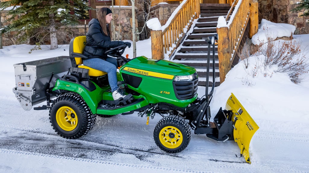 man on mower with cart attached going up a hill