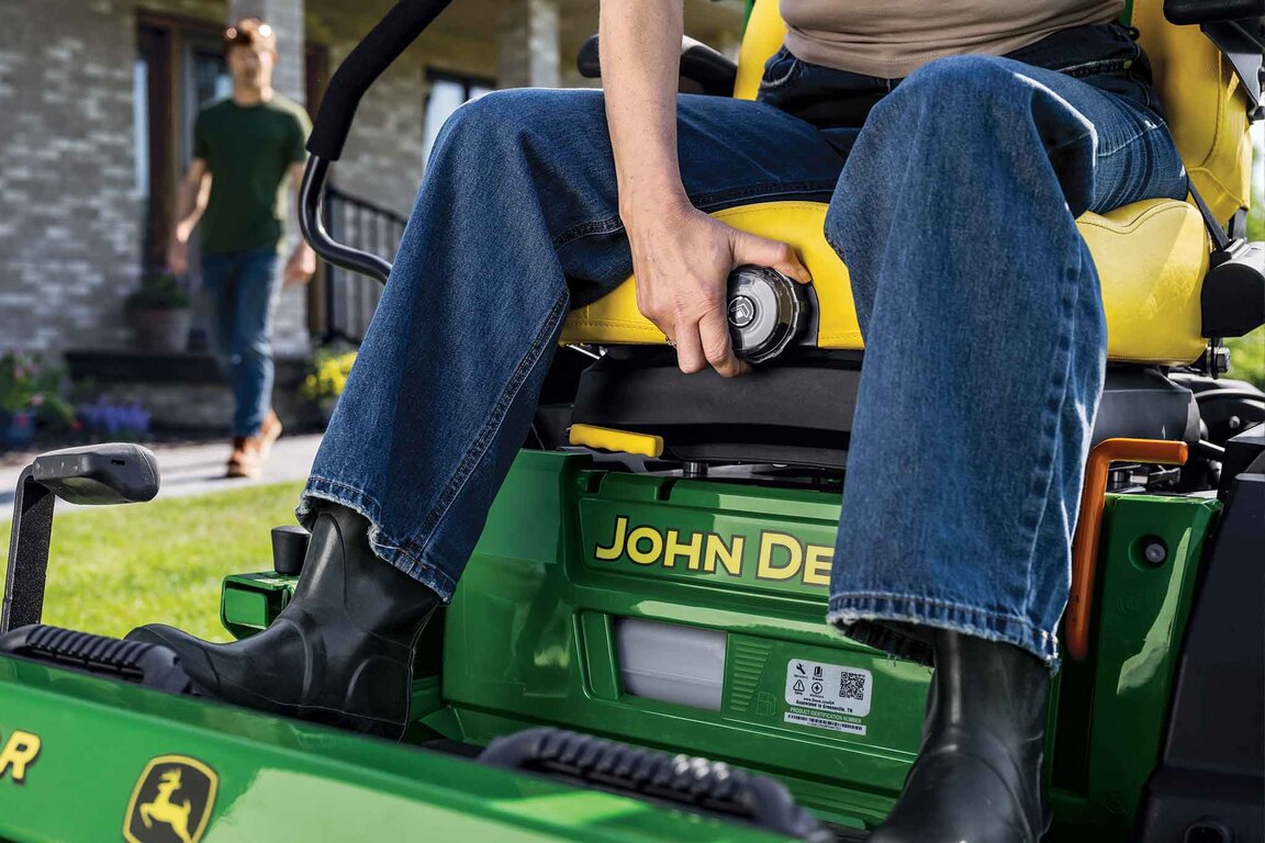 A close-up of a zero-turn mower driver turning the seat adjustment dial.