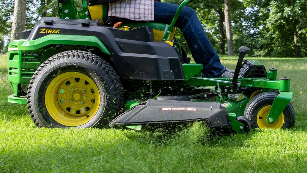 Gros plan sur un corps de tondeuse éjectant des brins d'herbe coupée