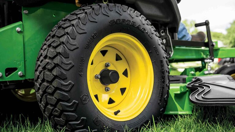 A close-up of a zero-turn mower tire with a yellow rim.