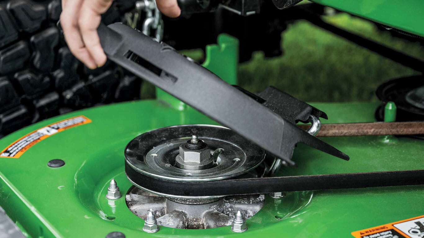 A close-up of the belt system on a green zero-turn mower deck.