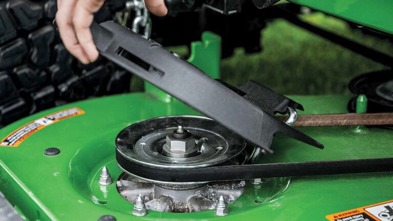 A close-up of the belt system on a green zero-turn mower deck.
