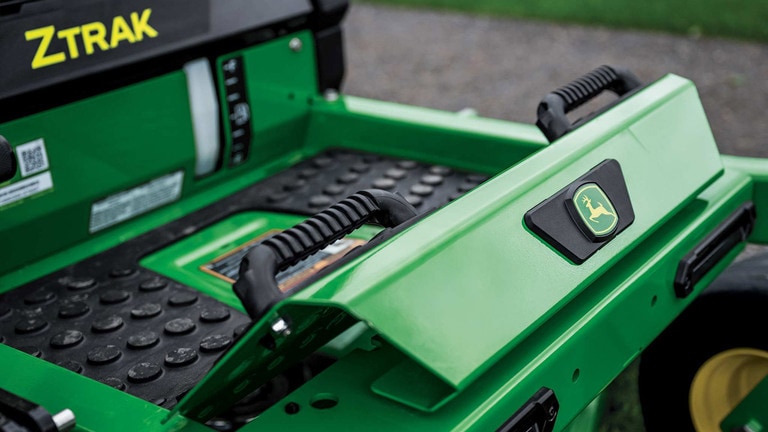 A zoomed-in shot of the footrest of a green zero-turn mower.