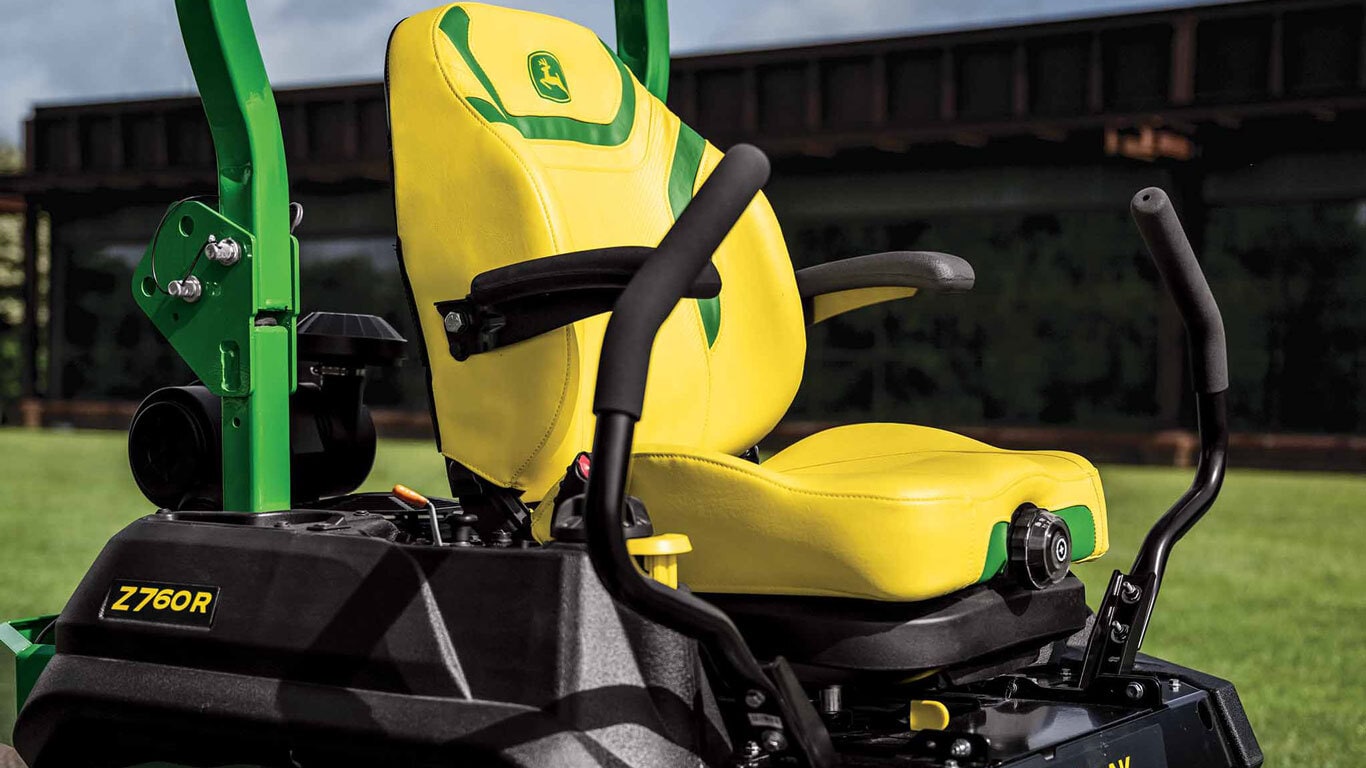 Une vue en gros plan du siège jaune d'une tondeuse à rayon de braquage nul, avec des détails verts, devant un édifice commercial.