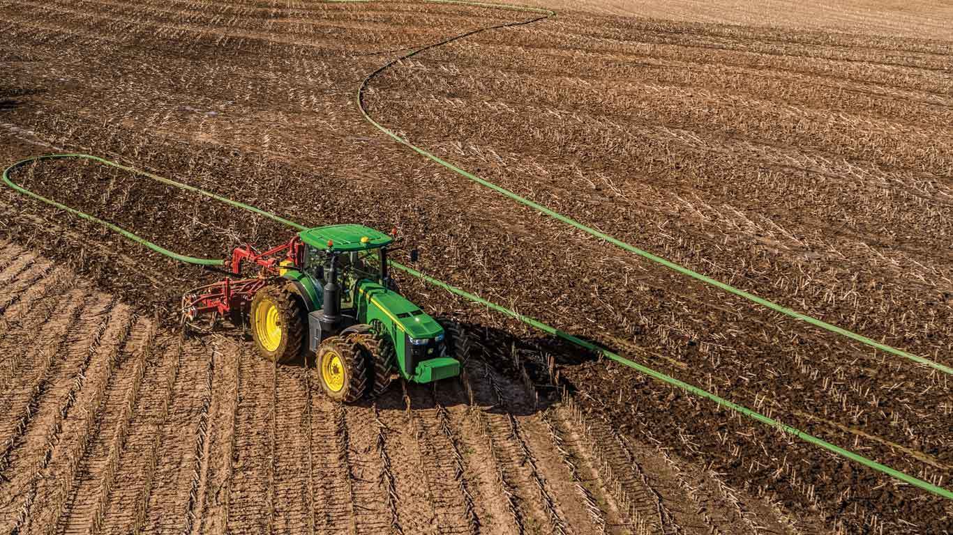 Vue aérienne d'un tracteur qui engraisse des champs récoltés