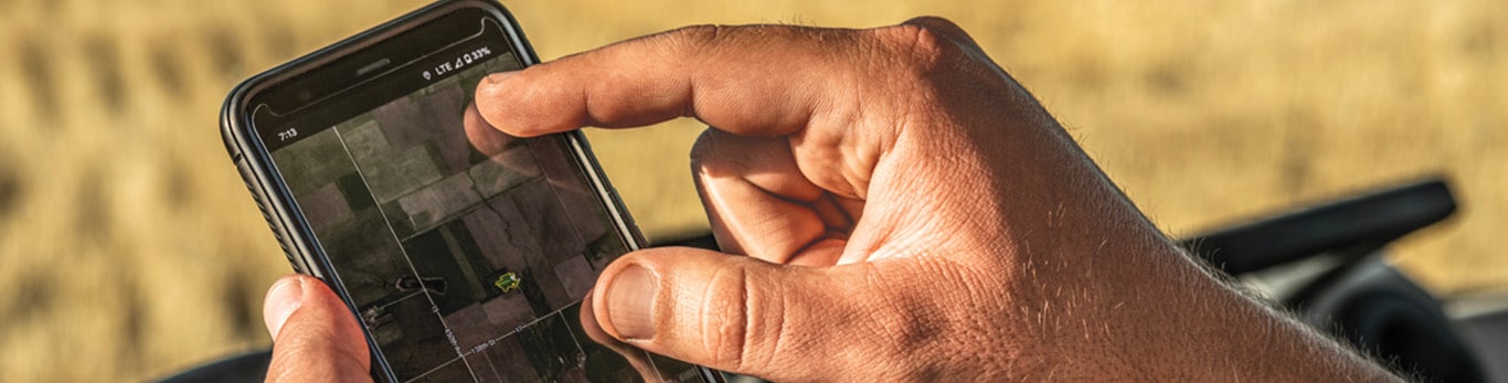 Man looking at a cell phone in front of a tractor