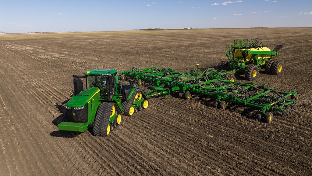 4WD Tractor pulling seeding equipment in field.