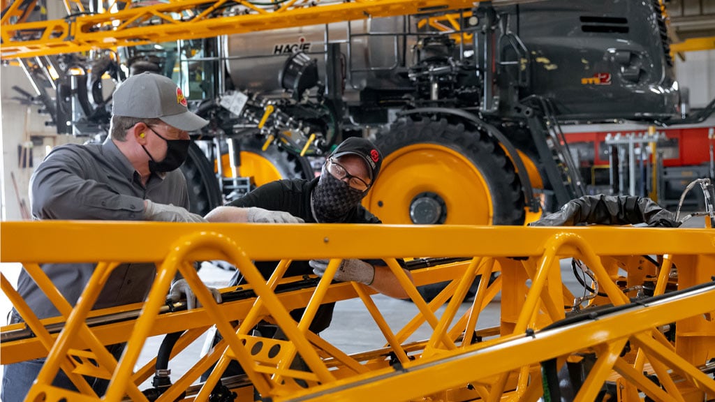 maintenance men working on hagie sprayer equipment