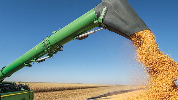 Close-up of a planter with large rubber wheels, preparing soil, generating dust in a field under bright sunlight.