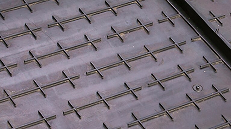 The crosshair design on the grain saver belts traps the grain to prevent it from rolling past the cutterbar onto the ground. 